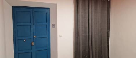 A room with a blue door, a grey curtain, and a patterned rug.
