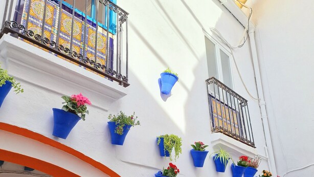 A building with white walls, orange arches, and blue flower pots. - Arc House Mezquita - Adults Only (Córdoba)