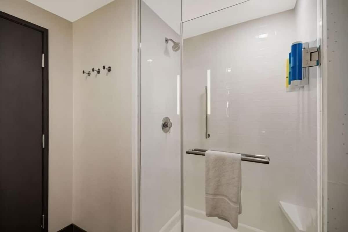 Una cabina doccia in vetro con porta e porta asciugamani.
