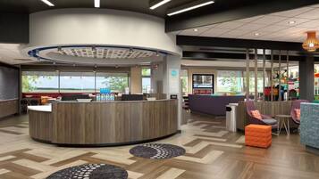 A modern reception area with a central desk, seating area with sofas, and a view of the outdoors.