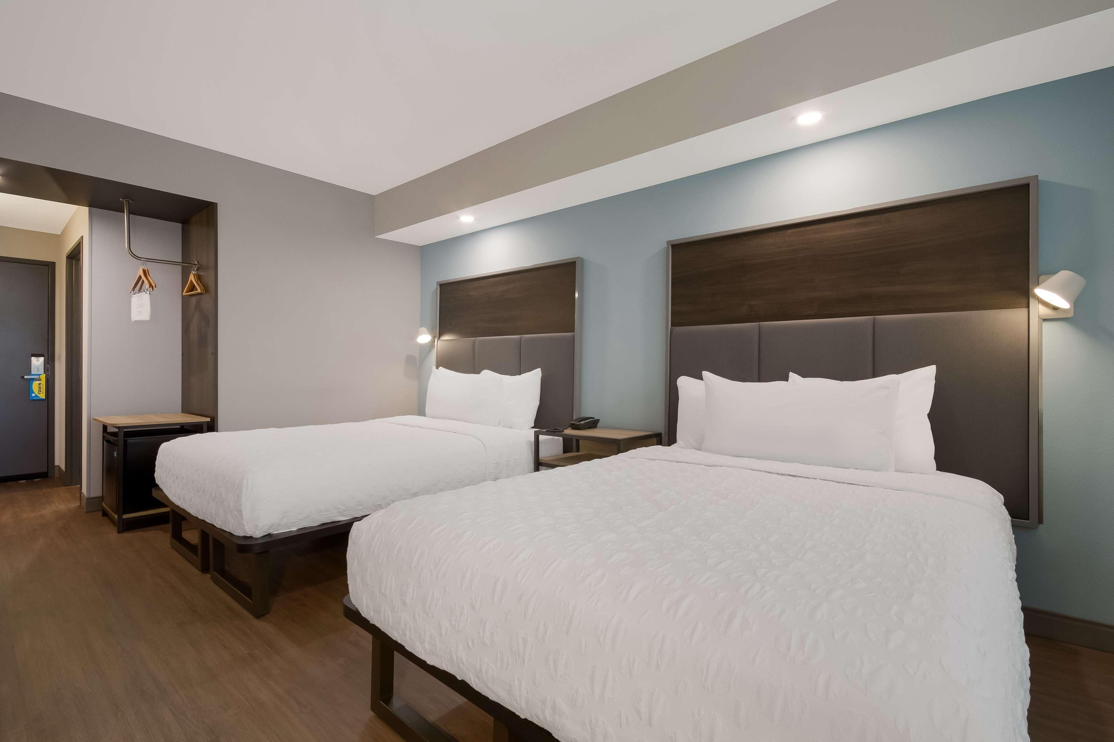 Een hotelkamer met twee bedden, een bureau en een kledingkast.