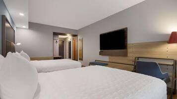 Een hotelkamer met twee bedden, een bureau, een stoel, een televisie en een wandlamp.