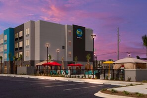 Un hôtel moderne, reconnaissable à son enseigne « tru by Hilton », doté de parasols sur la terrasse et d’un parking.