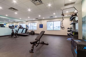 A fitness center with exercise equipment, a bench, and a treadmill. - Tru By Hilton Destin (Destin)