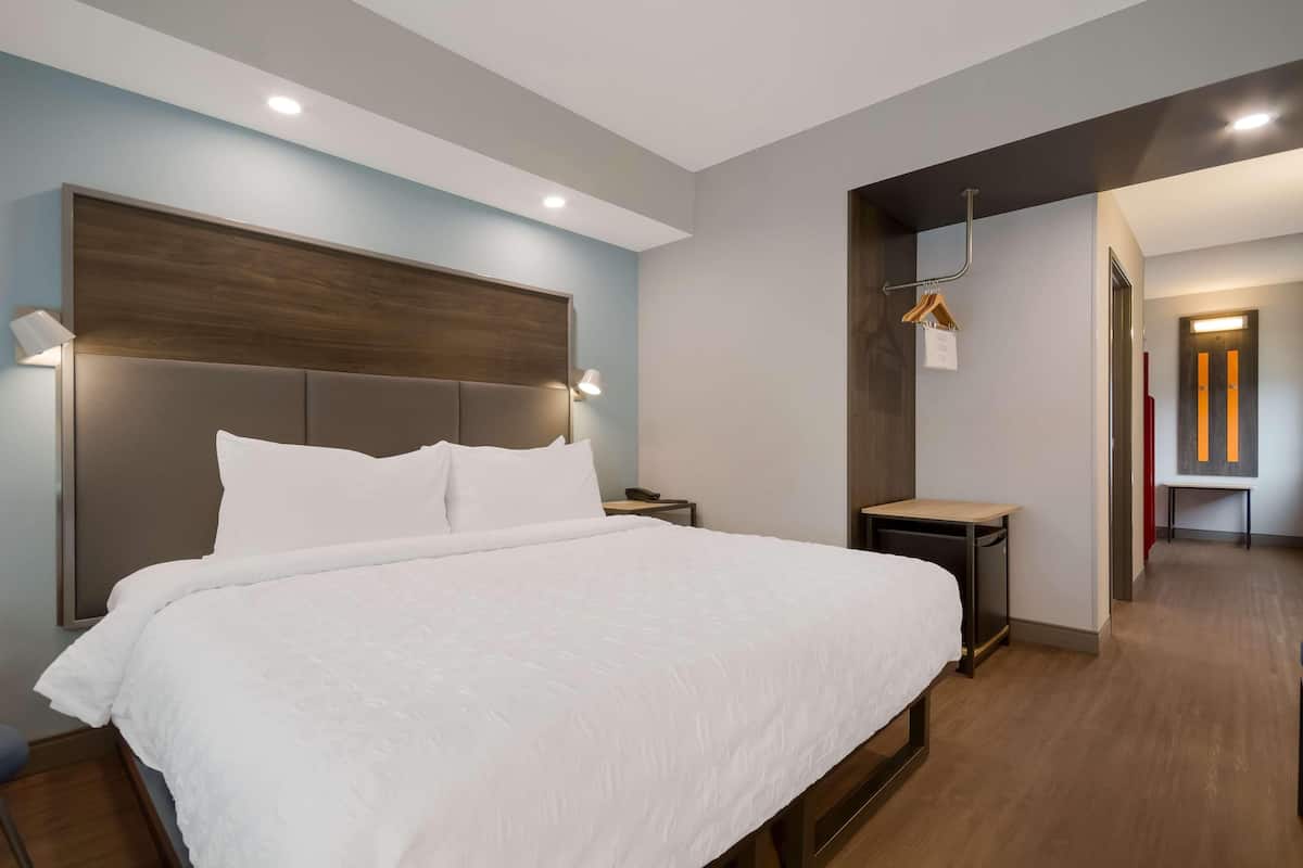 Una camera d'albergo moderna con un letto grande, comodini e una testiera in legno.