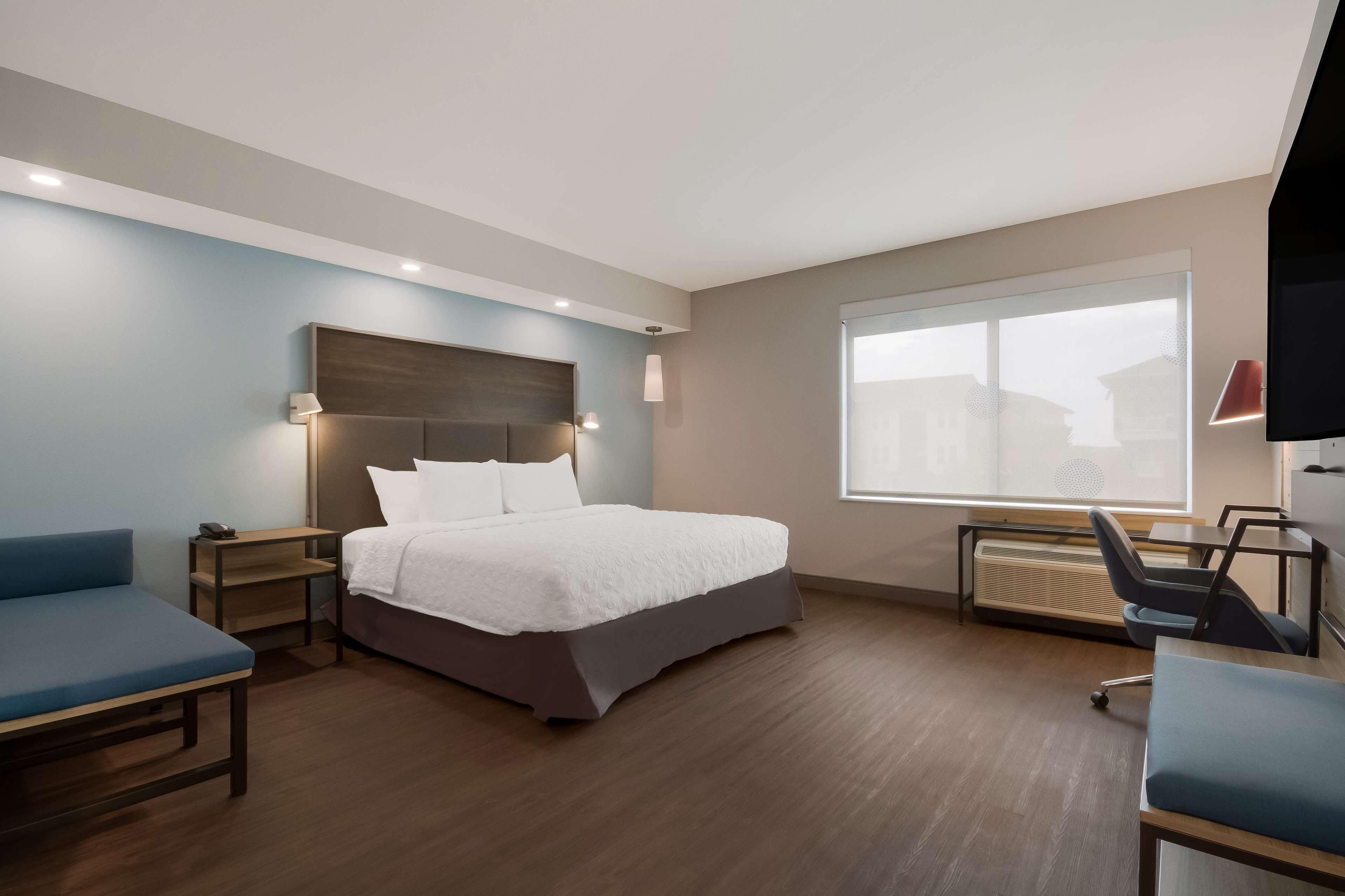 Een moderne hotelkamer met een groot bed, een bureau, een stoel en een televisie.