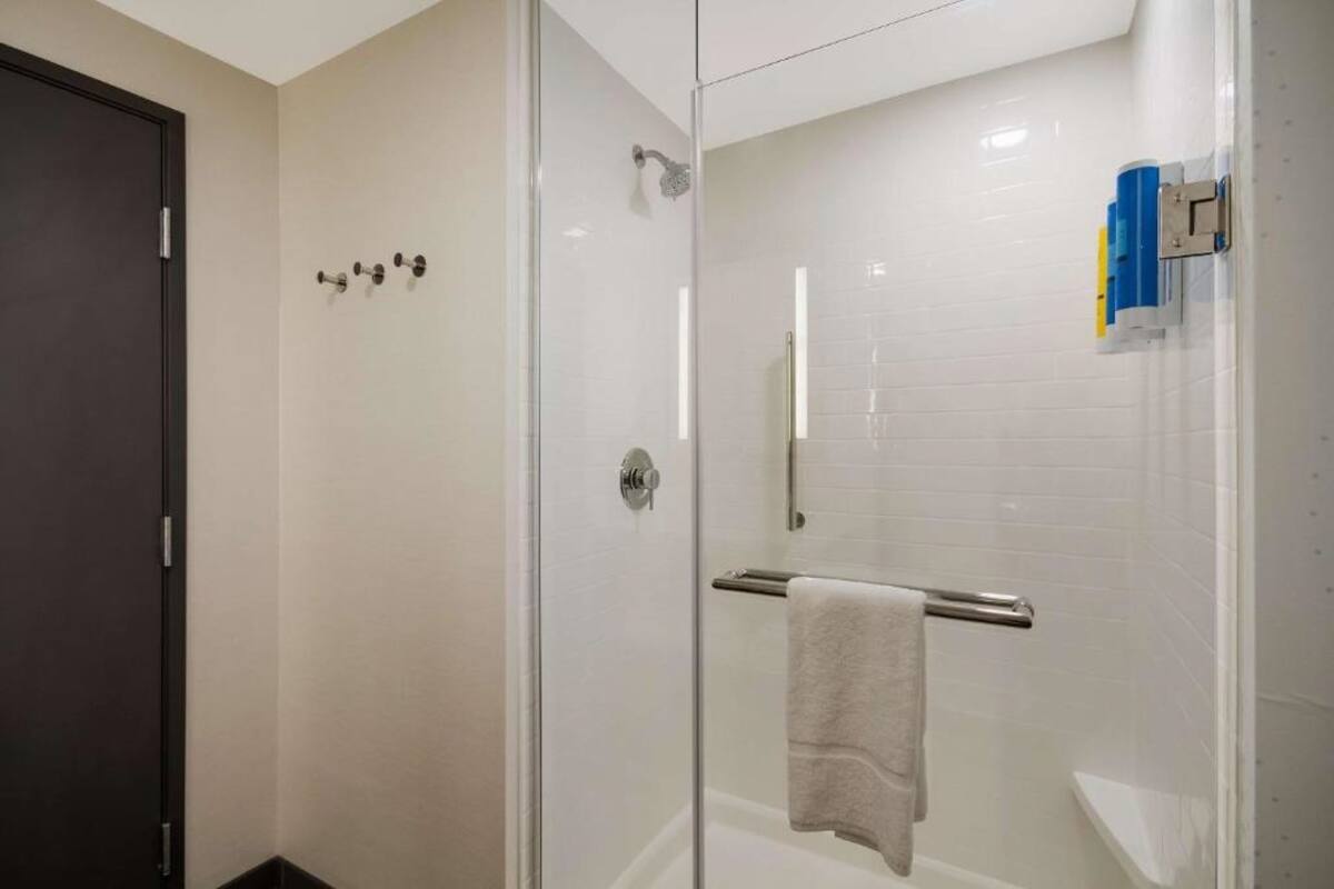 Un bagno moderno con box doccia in vetro, portasciugamani e porta carta igienica.