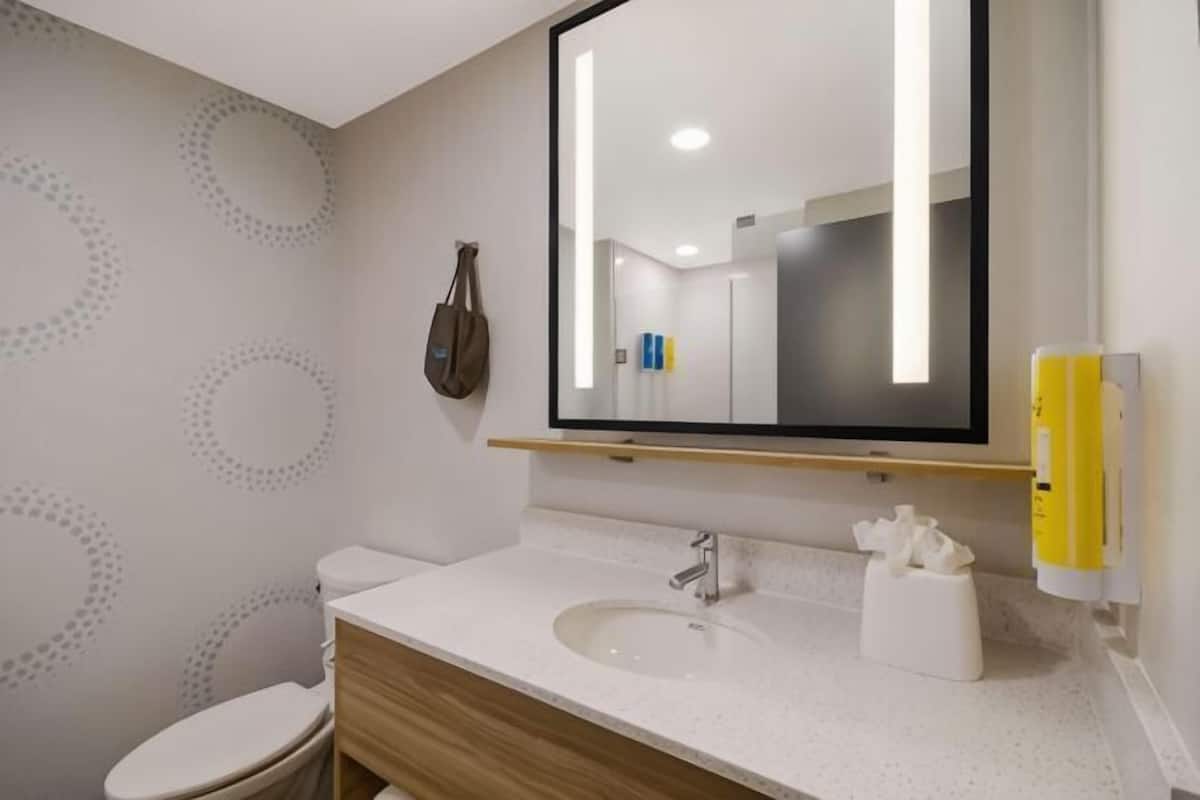 Un bagno con il water, lavandino, specchio e asciugatore a mano.