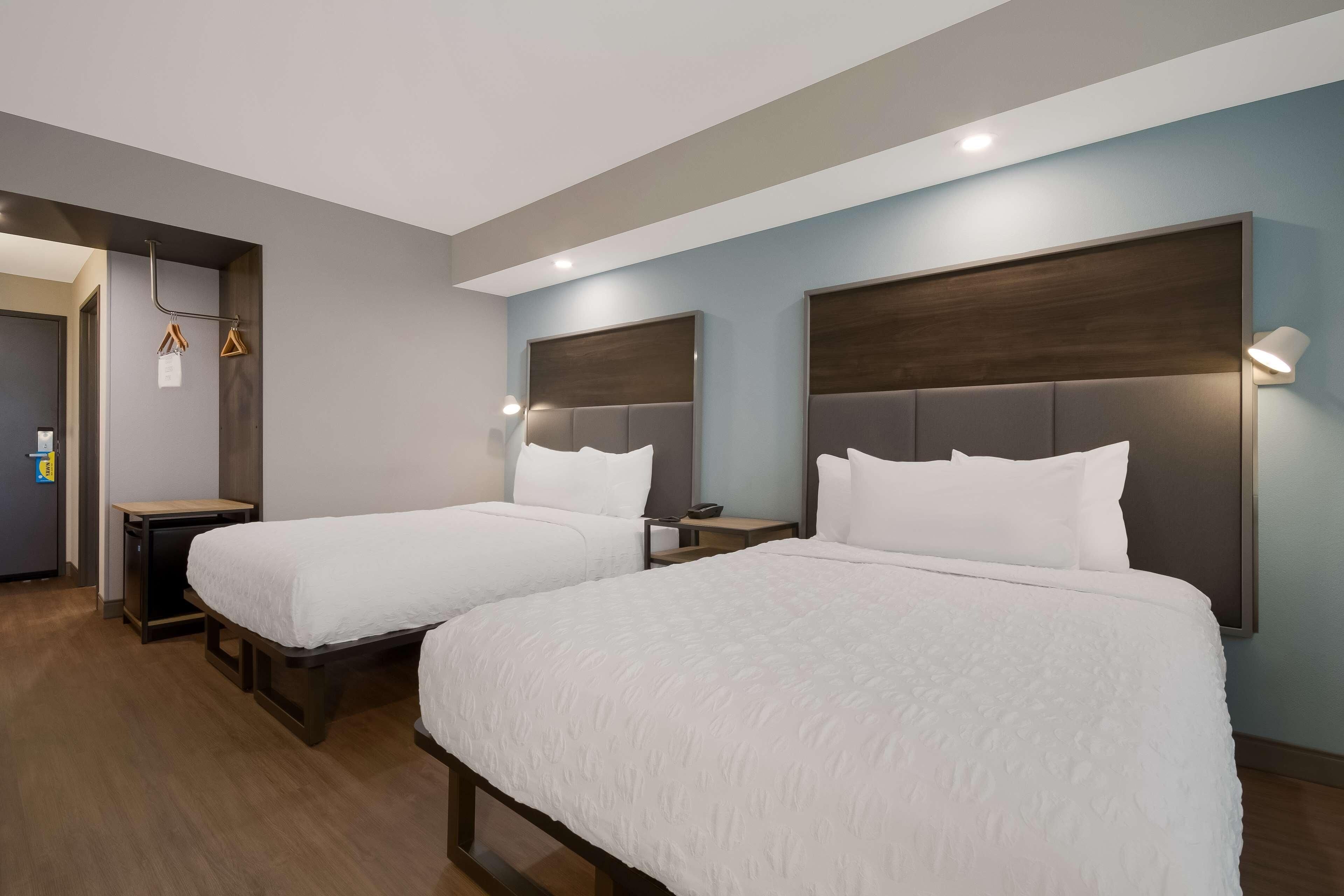 Quarto de hotel com duas camas, uma escrivaninha e um guarda-roupa.