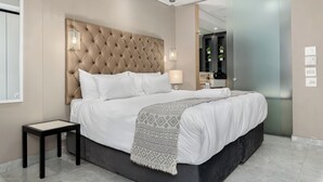Una camera da letto moderna con una testiera trapuntata, un letto grande, un comodino e uno specchio.