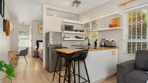 Een moderne keuken met een centraal eiland, barkrukken, een koelkast en een eetgedeelte met een stoel en tafel.