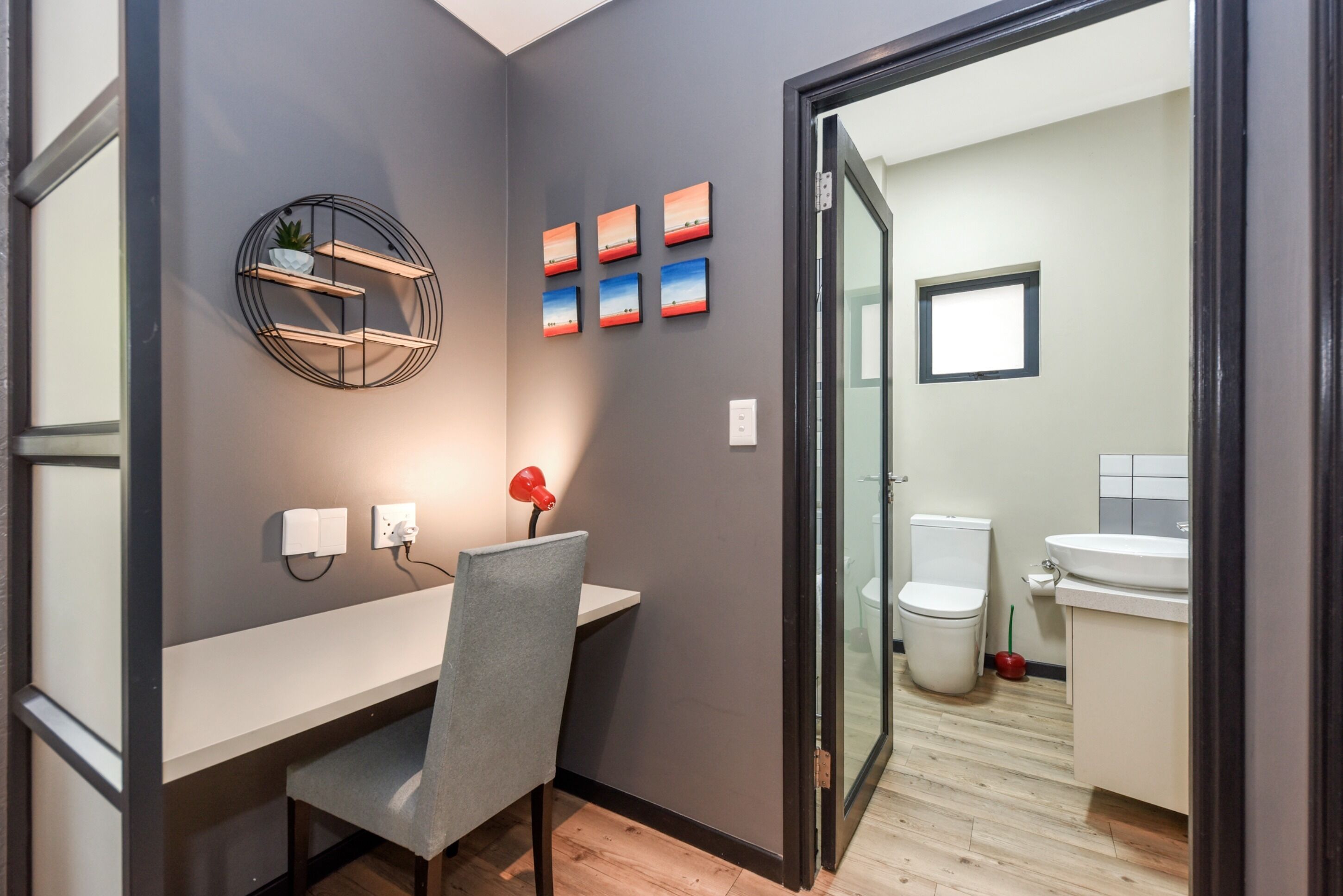 Et moderne badeværelse med toilet, håndvask og brusekabine i glas.