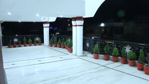 A spacious outdoor area with a tiled floor, potted plants, and a decorative railing.