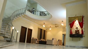 A spacious lobby with a marble floor, a curved staircase, and a seating area.
