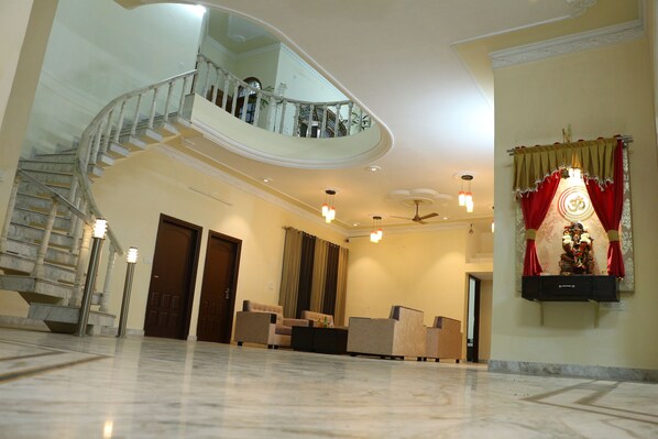 A spacious lobby with a marble floor, a curved staircase, and a seating area.