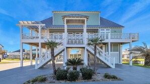 A two-story house with a balcony, a covered porch, and a staircase leading to the entrance. - A Wave From It All - Beautiful house, close to the beach with great views! (Crystal Beach)