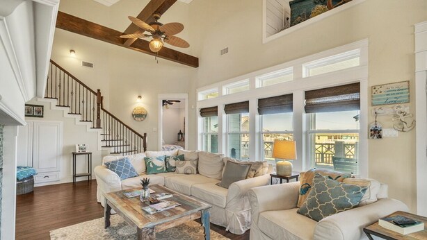 A spacious living room with a high ceiling, a wooden staircase, and large windows. - A Wave From It All - Beautiful house, close to the beach with great views! (Crystal Beach)