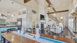 A spacious kitchen with white cabinetry, a wooden dining table, and a fireplace. - A Wave From It All - Beautiful house, close to the beach with great views! (Crystal Beach)