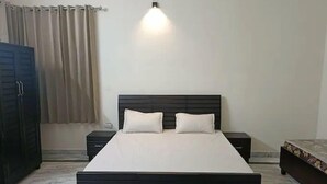A bedroom with a bed, two bedside tables, a wardrobe, and a wall-mounted light fixture. - Vehra Shagana Da, 4bhk, 2living (Jalandhar)