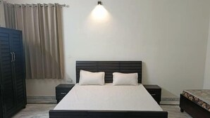 A bedroom with a bed, nightstands, a wardrobe, and a wall-mounted light fixture. - Vehra Shagana Da / 8 bedrooms/ Punjab (Jalandhar)