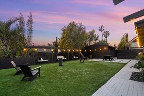 A backyard with artificial grass, a barbecue area, and outdoor seating.