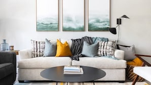Een woonkamer met een bank, een salontafel en drie ingelijste kunstwerken aan de muur.