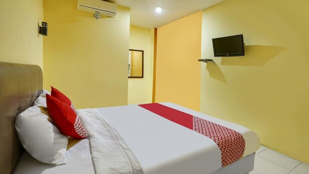 Une chambre d’hôtel équipée d’un lit, d’un téléviseur à écran plat fixé au mur et d’un appareil de climatisation.