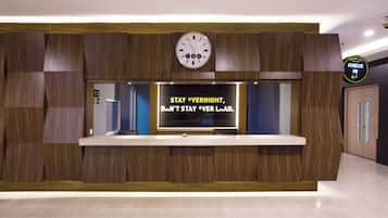 Uma mesa de recepção com um relógio em cima e uma placa que diz 'STAY OVERNIGHT, DON'T STAY OVER LOAF'.