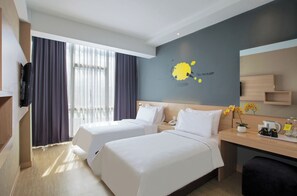 A hotel room with two beds, a desk with a coffee maker, a mirror, and a wall with a yellow artwork. - Rooms Inc BTC Pasteur (Bandung)