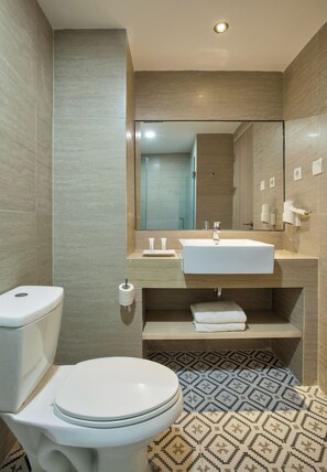 A modern bathroom with a toilet, sink, and mirror. - Rooms Inc BTC Pasteur (Bandung)
