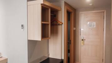 Ein Zimmer mit einem Holzschrank, einer verschließbaren Tür und einem kleinen Regal mit einer Fernbedienung.
