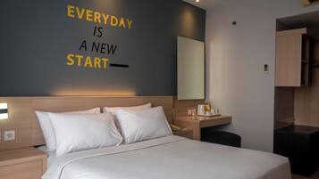 A hotel room with a bed, a bedside table, a nightstand, a mirror, and a wall with motivational text.