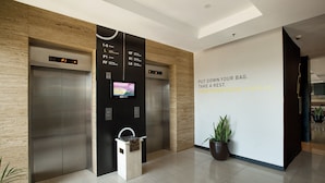 A modern elevator area with digital displays, a trash bin, and a motivational wall message. - Rooms Inc BTC Pasteur (Bandung)