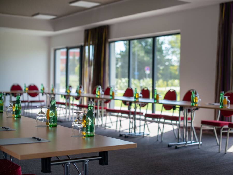 A conference room with tables, chairs, and bottles of water.
