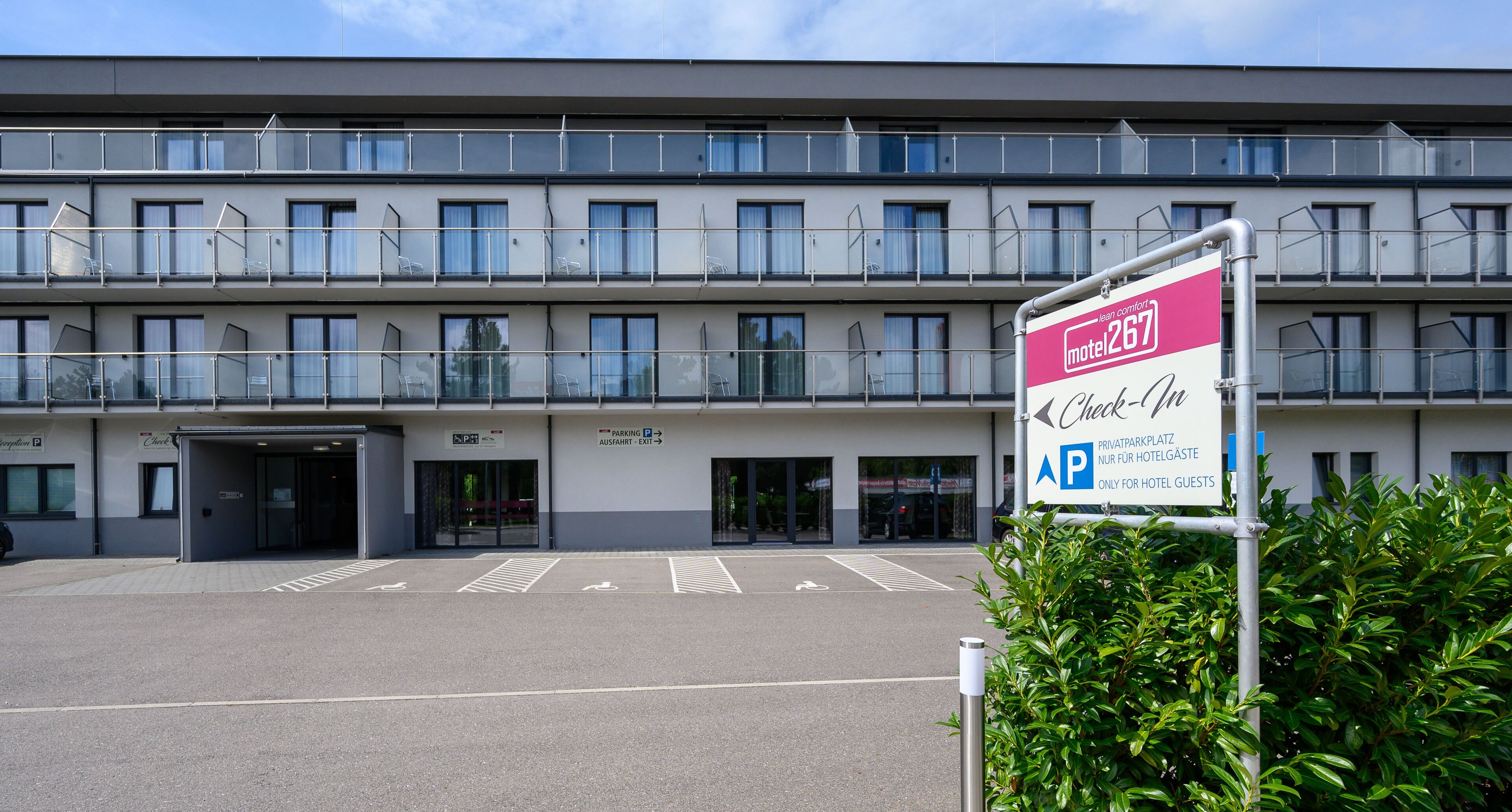 A hotel with a check-in sign, a parking sign, and a double-story building with balconies.
