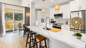 A modern kitchen with white cabinets, stainless steel appliances, and a large island with stools.