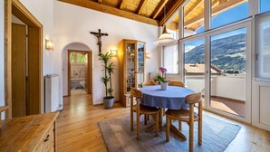 A wooden dining area with a table and chairs, a potted plant, and a view of the outdoors. - Holiday Apartment "Luisa" with Mountain View, Private Terrace & Wi-Fi (Schlanders)