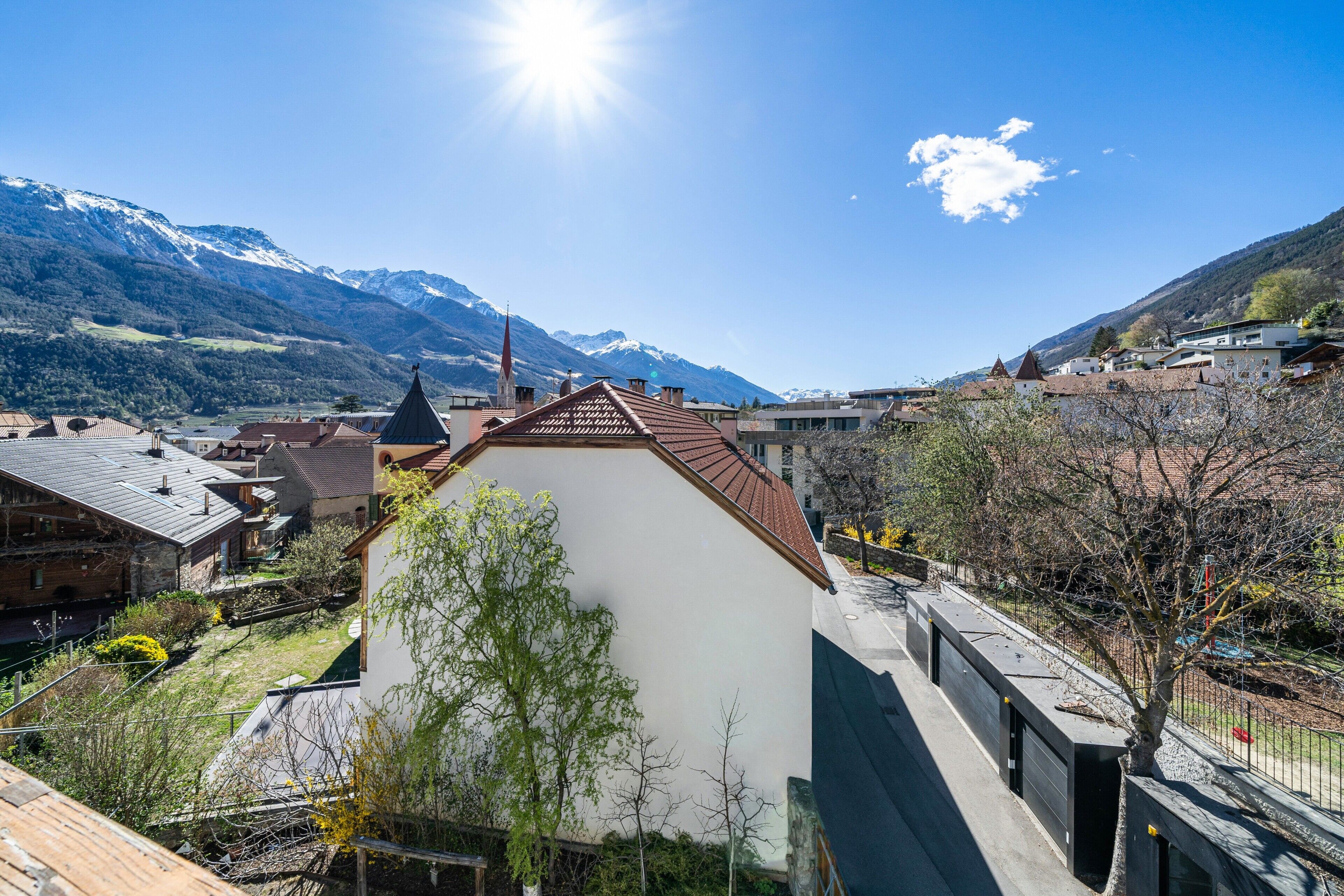A town with a prominent white building, a church, and mountains in the background.