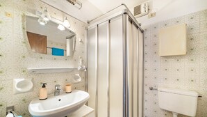 Un bagno con doccia, lavandino, specchio e toilette.