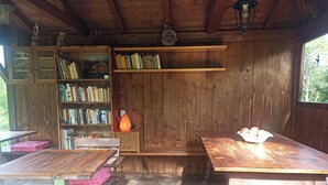 Un rustico chalet in legno con una libreria, un tavolo con una ciotola di frutta e una panca.