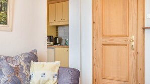 A room with a sofa, a wooden door, and a kitchen area in the background. - Apartment 'Adang Ferienwohnung Fernblick' with Mountain View, Shared Garden and Wi-Fi (Tirolo)