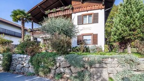 A two-story building with a stone wall, wooden balcony, and a sign that reads 'RODANG.' - Apartment 'Adang Ferienwohnung Fernblick' with Mountain View, Shared Garden and Wi-Fi (Tirolo)
