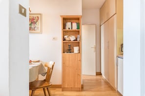 A hallway with a wooden cabinet, a dining table with chairs, and a door.