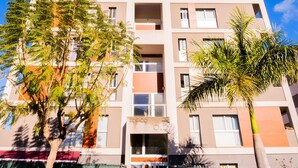 Un edificio de varios pisos con balcones, una entrada visible y cielo despejado.