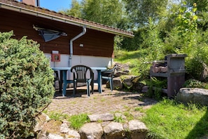 Una cabaña rústica con un patio de ladrillo, mobiliario exterior y una chimenea de piedra.