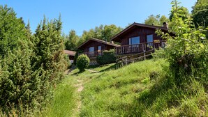 Two wooden cabins with balconies, surrounded by dense greenery and a clear sky. - Chalet 'Chalet Les Moraines 8' with Mountain View, Shared Pool and Private Terrace (Le Tholy)