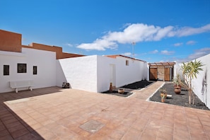 A courtyard with a white building, a bench, and potted plants.