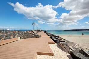 A wooden boardwalk leading to a sandy beach with a rocky shoreline and a clear blue sky. - Vacation Home 'Casa Vieja' with Mountain View, Private Pool and Wi-Fi (Puerto del Rosario)