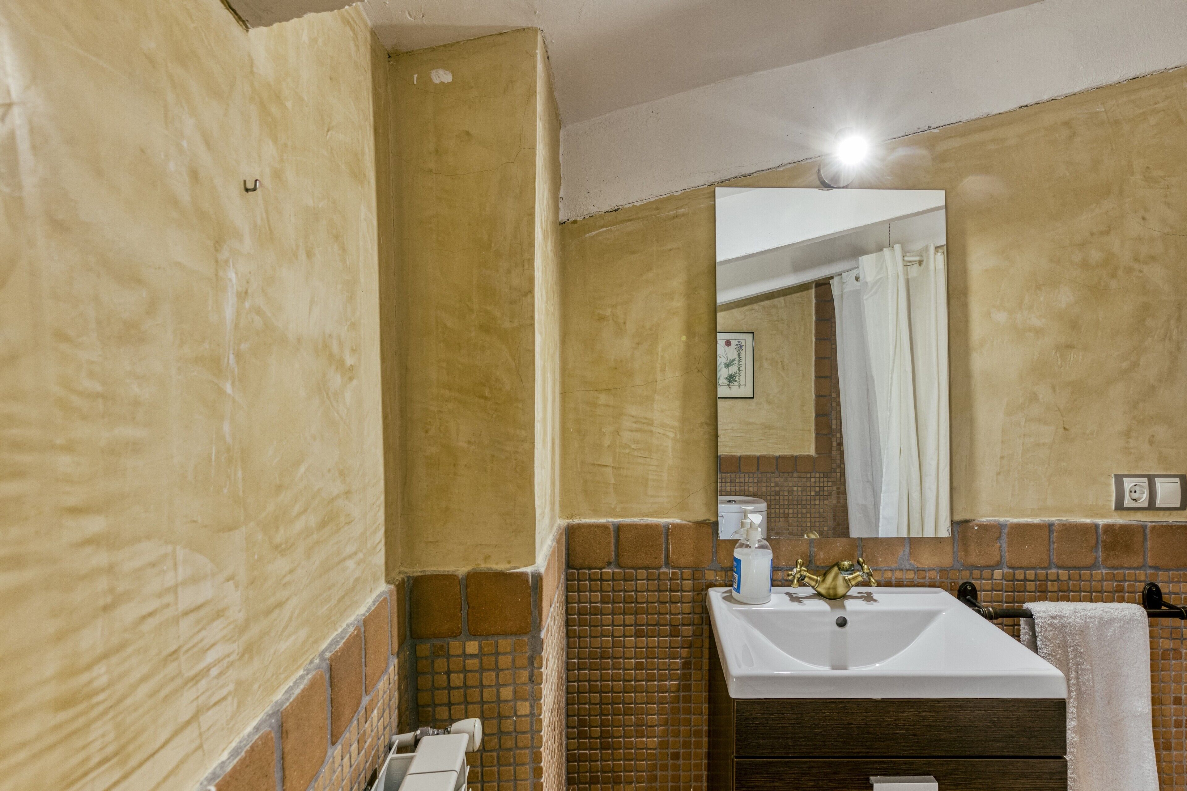 A bathroom with a sink, mirror, and tiled walls.
