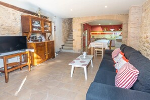 A living room with a TV, wooden cabinet, sofa, and a dining area with a table and chairs.